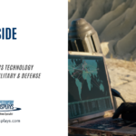 A blog post graphic with the title "NVIS INSIDE AND OUT" in large blue text. Below, smaller grey text reads "A LOOK INSIDE NVIS TECHNOLOGY THAT'S USED IN MILITARY & DEFENSE APPLICATIONS". To the right, a slightly blurred image shows a person in military camouflage gear using a laptop computer with a world map displayed on the screen. The person is also holding a radio communication device. The background shows a dry, rocky landscape. The "AGDisplays" logo and website address are in the bottom left corner.