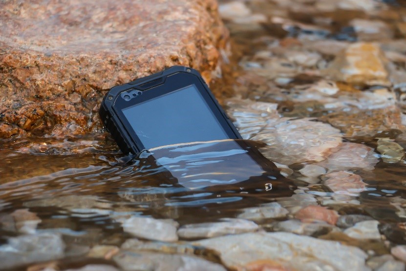 A rugged tablet half submerged in a stream of water