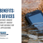 A blog post header from AGDisplays titled "TOP 10 BENEFITS: RUGGED DEVICES." The text on the left side of the image mentions MIL-STD-810G ratings, rugged features, and portability, stating that rugged mobile devices are suitable for all industrial applications. The right side shows a rugged tablet partially submerged in a shallow stream, demonstrating its waterproof capability. The AGDisplays logo and website are at the bottom of the text section.