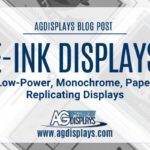 A background of slightly overlapping and angled grayscale images of E-Ink display panels showing ticket designs, overlaid with a white banner stating "AGDISPLAYS BLOG POST" at the top, followed by "E-INK DISPLAYS Low-Power, Monochrome, Paper Replicating Displays," and the AGDisplays logo with "www.agdisplays.com" at the bottom.