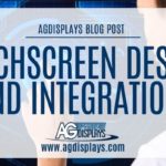 A slightly blurred image of a person interacting with a digital touchscreen interface displaying technical diagrams and data visualizations, overlaid with a white banner stating "AGDISPLAYS BLOG POST" at the top, followed by "TOUCHSCREEN DESIGN AND INTEGRATION," and the AGDisplays logo with "www.agdisplays.com" at the bottom.